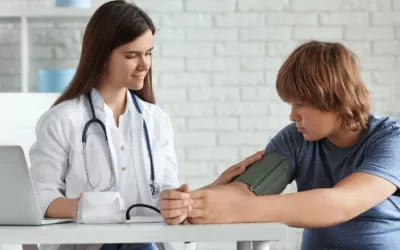 Doctora mide la presión arterial de un adolescente con sobrepeso Doctora toma la tensión arterial a un adolescente