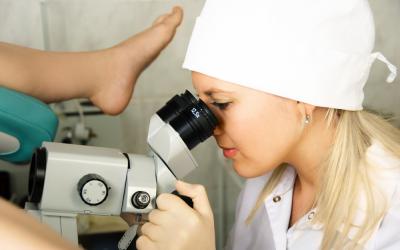 Una doctora usa un colposcopio para observar el cuello uterino de una paciente