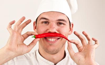 Un cocinero huele un pimiento picante que sostiene en sus manos