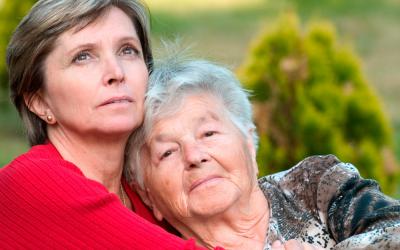 Una cuidadora abraza a una anciana en situación de dependencia