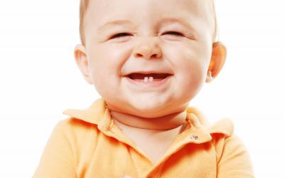 Un bebé sonríe mostrando sus primeros dientes