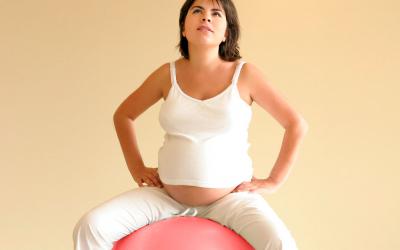 Mujer embarazada sentada sobre pelota de gimnasia