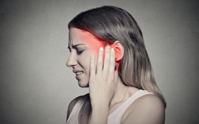 Mujer joven con tinnitus se toca la sien